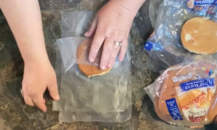 person wrapping bun in plastic wrap