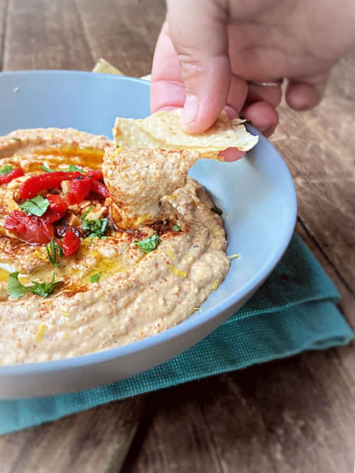 chip dipping hummus from bowl