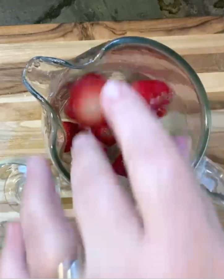 hand adding fruit to glass