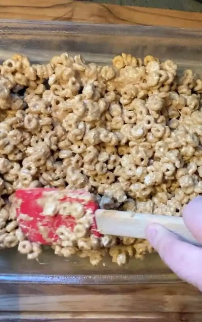 spreading peanut butter cheerio bars ingredients in pan