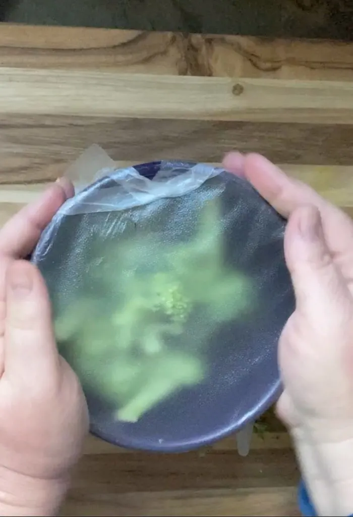 broccoli in bowl with plastic wrap