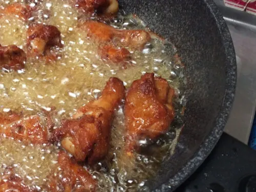 Chicken cooking in a skillet with oil