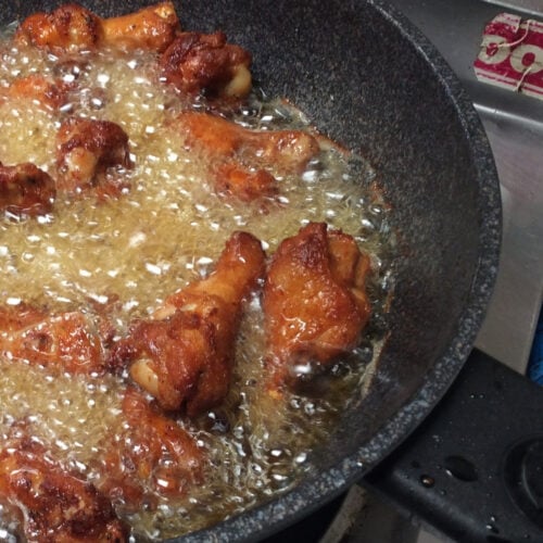 Chicken cooking in a skillet with oil