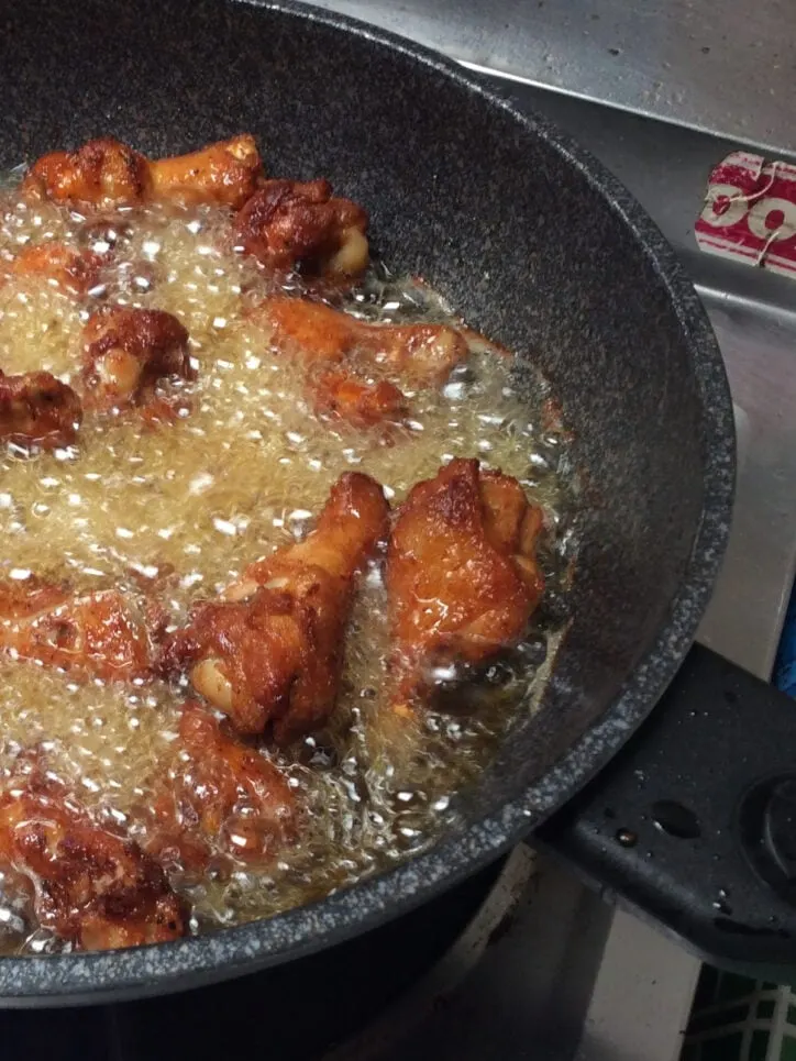Chicken cooking in a skillet with oil