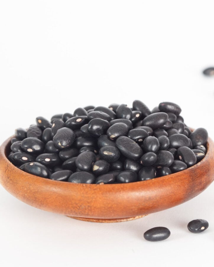 dry black beans in a wooden bowl.