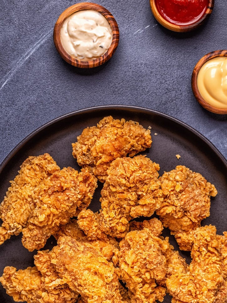 Fried chicken in a pan with sauces. 
