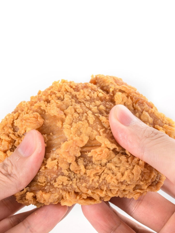 piece of fried chicken in someones hand.