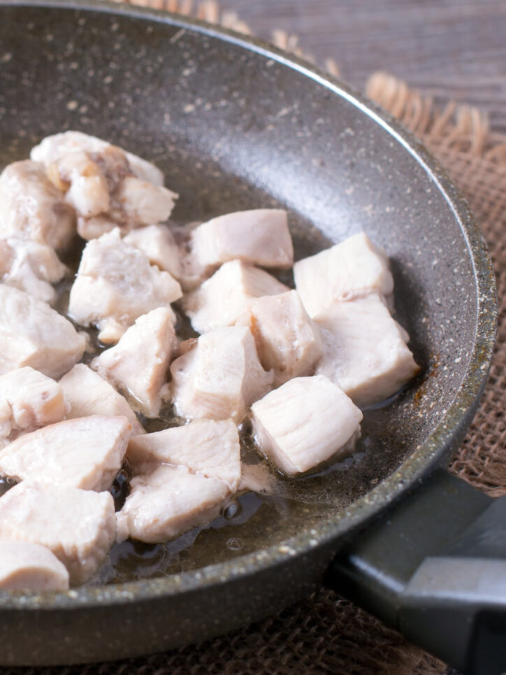 Chicken pieces in a pan.