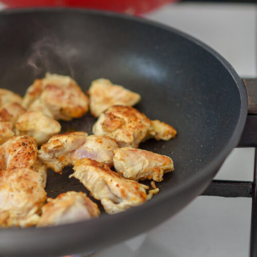 Chicken pieces browning in a pan.