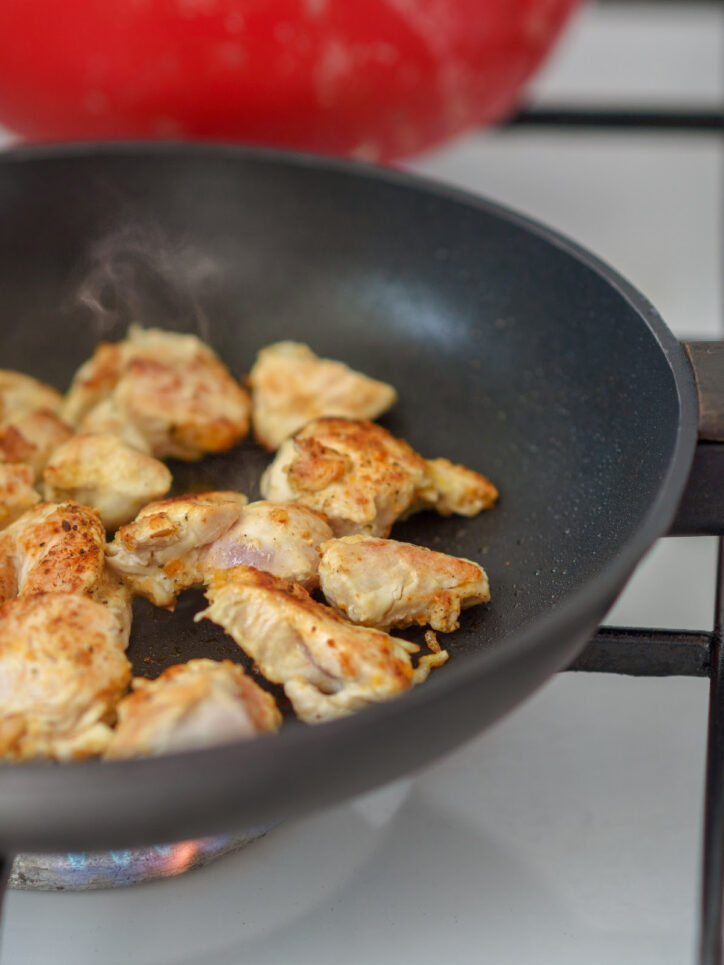 Chicken pieces browning in a pan.