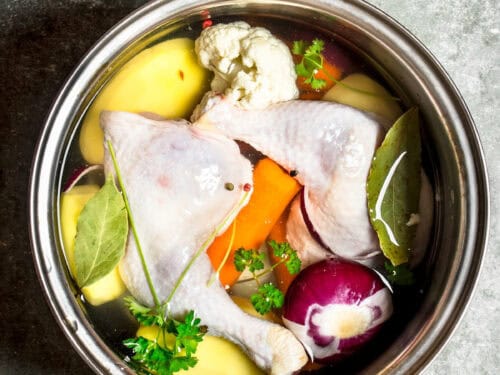 Preserving Chicken Stock Recipe raw chicken, herbs, and vegetables in a pot with water