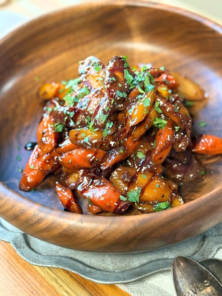 glazed tri-colored carrots in a bowl with parsley and balsamic glaze on top