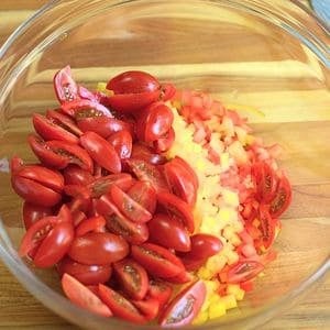 Chopped bell peppers, and cherry tomatoes in a glass bowl