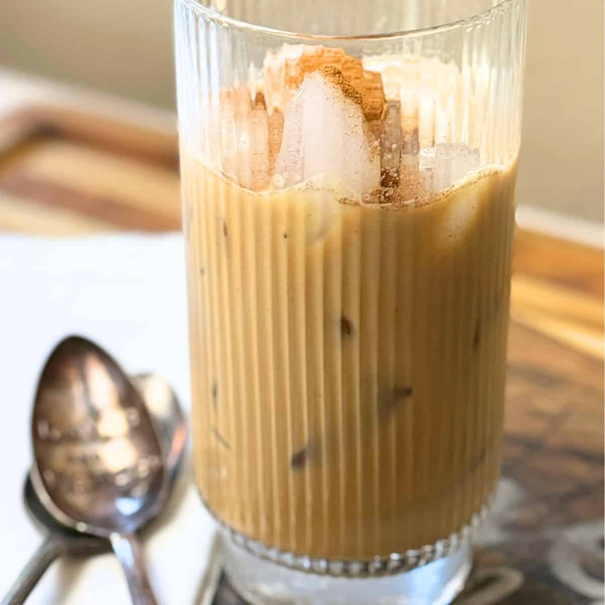 Close-up of Vietnamese iced coffee showing layered appearance with ice cubes and coffee in a ribbed glass, with a spoon visible in the foreground.