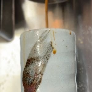 Espresso being brewed into a ceramic cup
