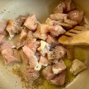 raw chicken pieces in a pot with seasonings