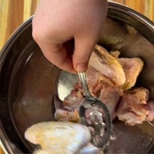 a person is mixing the wings in the bowl to help distribute the oil, and spices