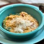 cheesey chicken and orzo in a blue dish with spinach and a spoon