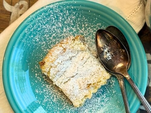 gooey butter cake from over head with two spoons, on a blue plate with a white napkin