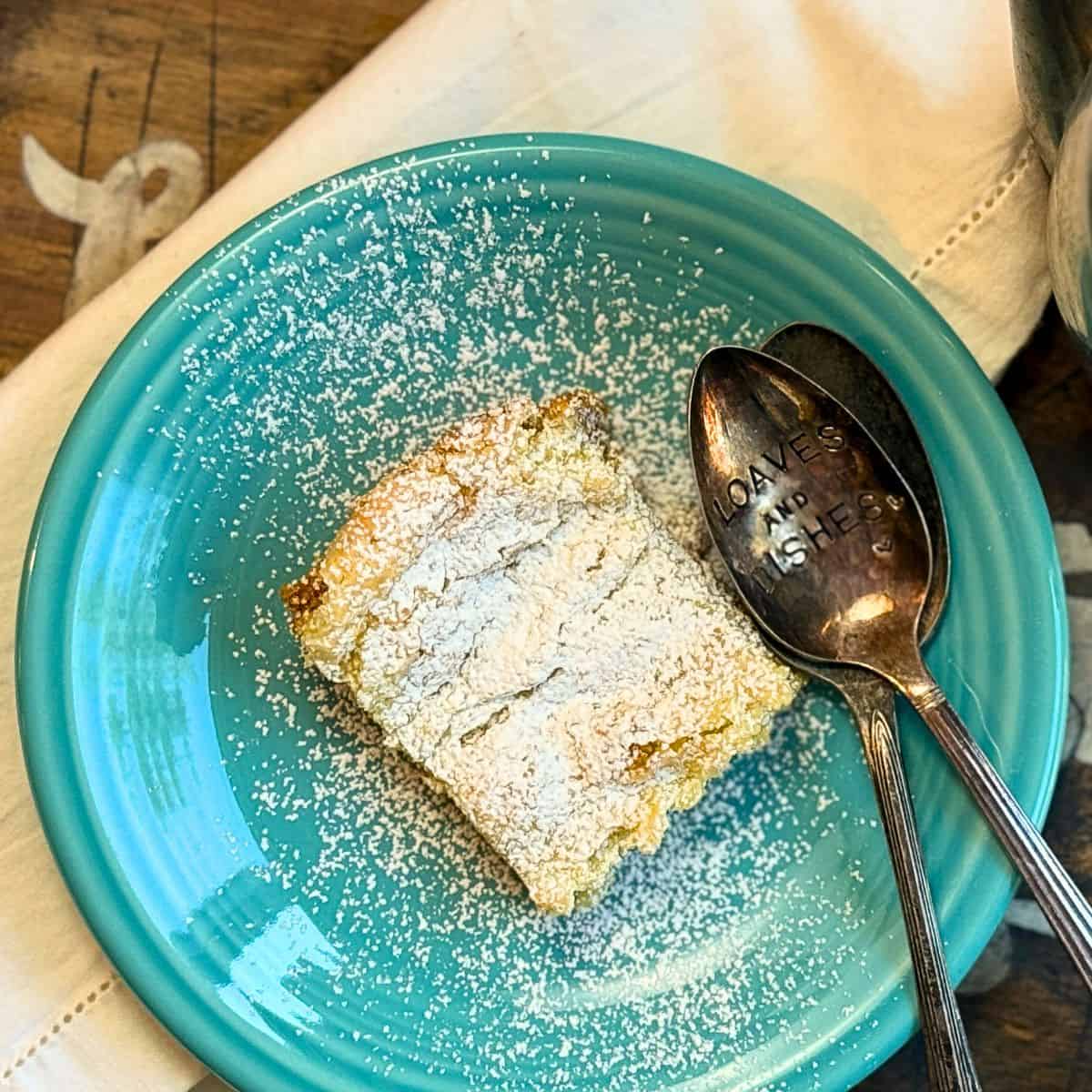 gooey butter cake from over head with two spoons, on a blue plate with a white napkin