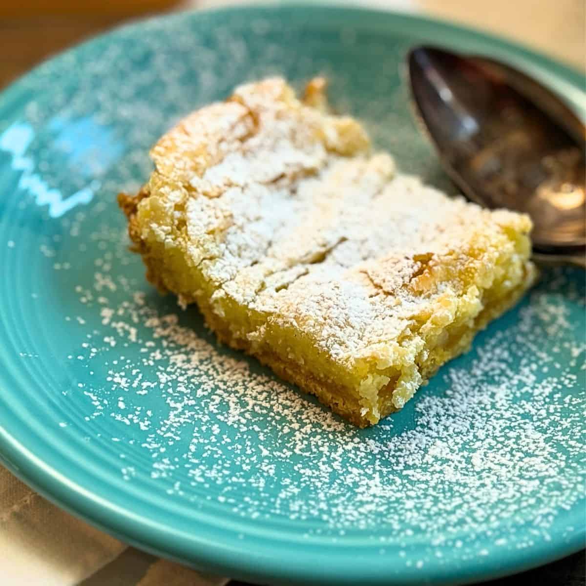 gooey butter cake on a plate close up sprinkled with powdered sugar