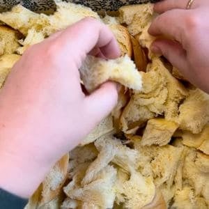 hand tearing bread into bite size pieces