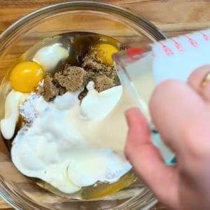 pouring heavy cream into a bowl with eggs and brown sugar