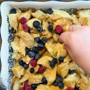 putting berries on top of overnight french toast casserole before baking