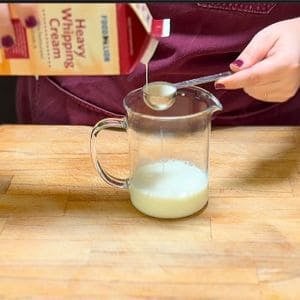 measuring heavy cream into a glass