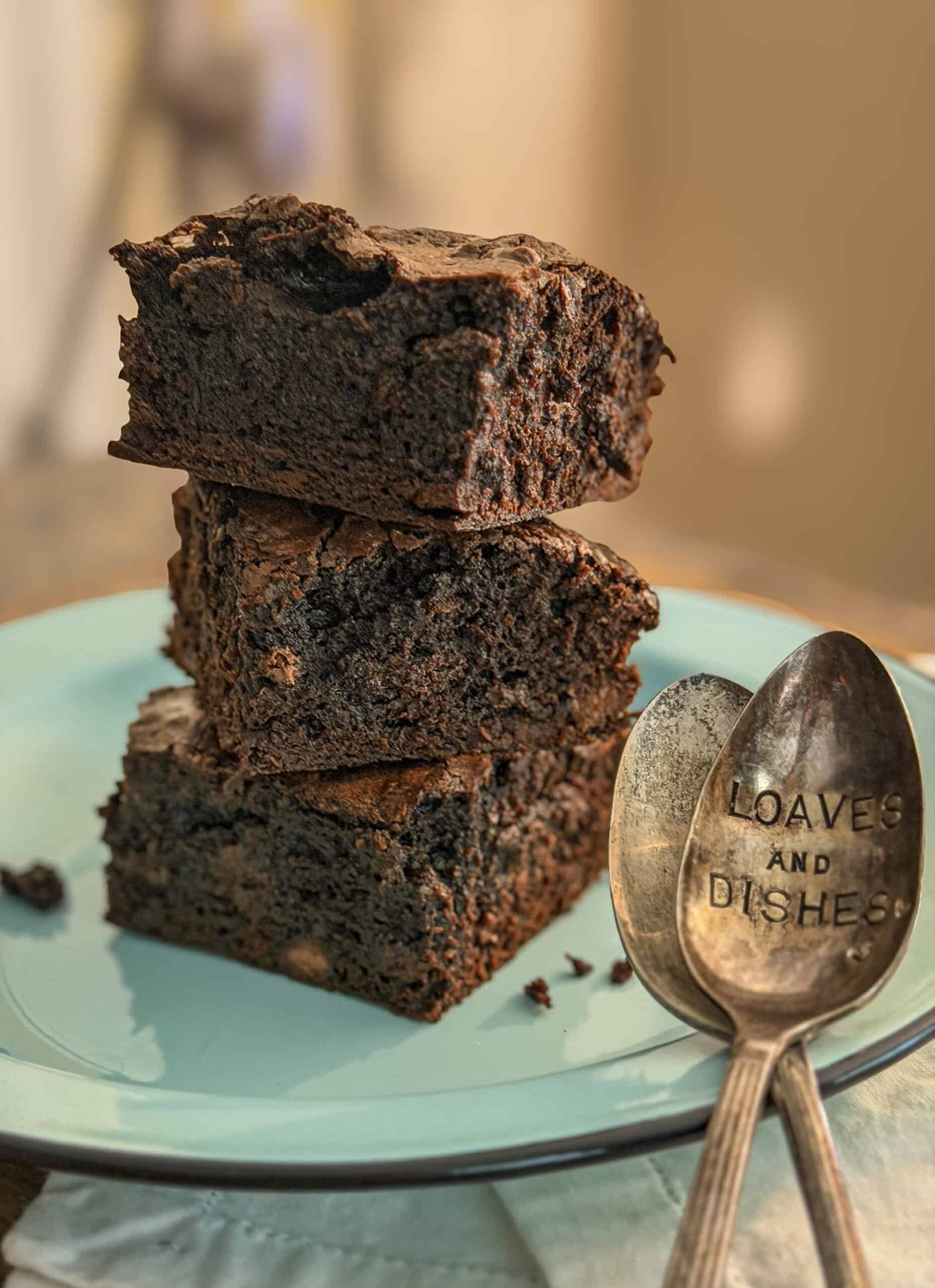 Close-up of three stacked homemade chocolate brownies with a rich, fudgy texture and crackly tops.