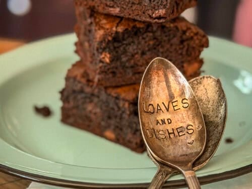 The Best Fudgy Brownies Three thick, fudgy chocolate brownies stacked on a plate, showing a dense, moist crumb with chunks of melted chocolate.