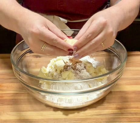 Cold cubed butter being added to flour and spices while making a copycat Starbucks pumpkin scone recipe.